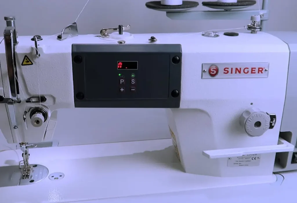 Uma máquina de costura singer industrial reta em uma mesa.